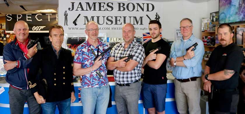 group photo of museum visitors brandishing toy guns and posing with owner